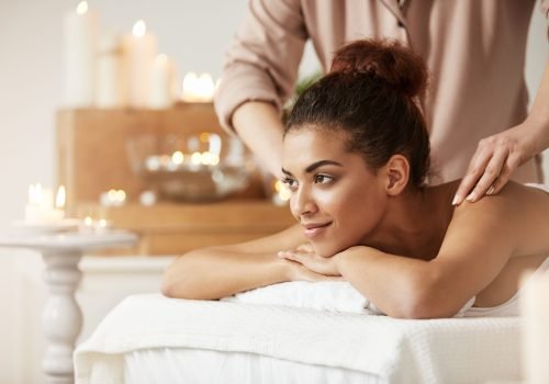 Young beautiful african girl smiling enjoying massage in spa resort.